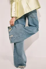 Pantalón de jean celeste de corte wide leg con roturas en las rodillas.