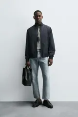 Cazadora de corte regular confeccionada en tejido técnico repelente al agua. Presenta cuello subido, manga larga con puños de rib, bolsillos laterales de vivo y cierre frontal con cremallera.