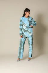 Pantalón de jogging con estampado batik en tonos celeste, gris y blanco. Pierna recta con abertura lateral, cintura elástica y bolsillos laterales.