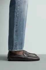 Mocasín de vestir en piel color marrón oscuro, con detalle de antifaz en el empeine, horma redonda y suela de goma Vibram.