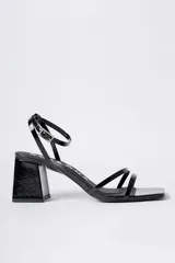 Sandalias de tacón cuadrado medio, color negro con acabado brillante, diseño de tiras finas en el empeine y cierre de pulsera con hebilla al tobillo.