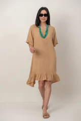Vestido midi de lino color beige, de corte relajado y mangas cortas. Presenta cuello redondo, detalle de alforzas verticales en el centro del pecho y volados en el ruedo.