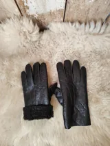 Guantes de cuero marrón oscuro, cortados y cosidos a mano, con detalle de borde de piel sintética en las muñecas.