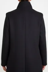 Saco de paño negro de corte recto, con cuello solapa, cierre frontal con botones y bolsillos laterales con solapa.