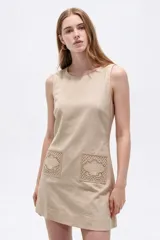 Vestido corto blanco de viscosa, sin mangas, con cuello redondo a la base y bolsillos frontales con apliques bordados.
