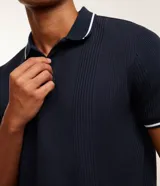 Remera polo blanca de viscosa texturizada con rayas, cuello y puños de mangas cortas en ribana con detalles contrastantes en negro.