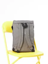 Mochila color beige de lona 100% poliéster, con correas de ajuste frontales color verde oliva y logo de la marca bordado.