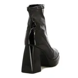 Bota corta de mujer color negro, con acabado charol brillante. Presenta un taco ancho y alto, y una plataforma delantera. El caño es ajustado, tipo calcetín, con textura elástica en el borde superior.