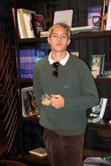 Buzo de punto color verde oscuro, de manga larga y diseño clásico con cuello redondo y pequeño bordado en el pecho.