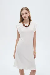 Vestido midi de poliéster color blanco, de corte recto y escote redondo a la base, con mangas cortas abuchonadas con volados y detalles de volados en el ruedo.