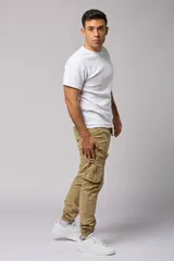 Pantalón cargo color beige de gabardina, con corte ajustado, bolsillos laterales con fuelle y puños elásticos en los tobillos.
