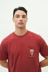 Remera de manga corta color ladrillo con bolsillo en el pecho y estampado pequeño de una palmera.