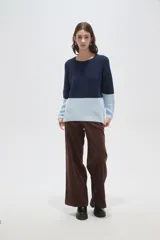 Sweater de tejido de punto con diseño color block, combinando azul marino en la parte superior y celeste en la inferior. Presenta cuello redondo a la base y mangas largas.