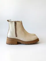 Bota corta de cuero vacuno con textura granulada, color crudo. Presenta cierre lateral metálico, suela track de goma en tono suela y tirador trasero.