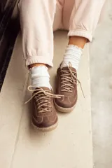 Zapatilla de cuero vacuno color marrón con cordones y suela de goma.