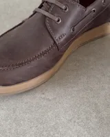 Zapato náutico marrón de cuero vacuno con cordones y suela plana.