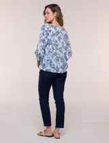 Blusa holgada de rayón y poliéster, marca Zac & Rachel, con estampado floral en tonos azules sobre fondo blanco. Posee escote en V con muesca central, mangas largas abullonadas con inserción de puntilla y puños elastizados.