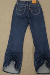 Jeans de denim azul oscuro con lavado vintage, tiro alto y corte acampanado.