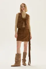 Falda corta de cuero color marrón, con diseño de flecos largos desmontables que cubren toda la prenda. Presenta un estilo western con cierre en la cintura.