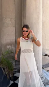 Vestido largo de red color blanco roto, sin mangas y con tajo lateral. Se usa sobre otra prenda interior.