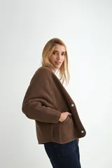 Campera corta de paño color negro, con cuello redondo, mangas largas y cierre frontal con botones a presión metálicos.