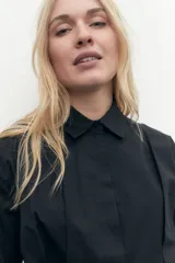 Camisa corta blanca de mangas largas con puños abotonados y cuello clásico.