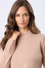 Buzo tejido de lana con cuello alto, diseño de punto grueso, tajos laterales y en puños. Presenta terminaciones acanaladas en puños y cintura, con un parche decorativo en la parte inferior.