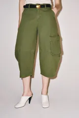 Jeans capri de tiro medio y corte balloon leg en color verde militar. Presenta trabillas en la cintura, bolsillos laterales y bolsillos de plastrón tipo cargo en las piernas. Cuenta con cierre frontal con cremallera y botón metálico.