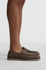 Mocasín casual de piel con acabado nobuck, color marrón claro. Presenta un corte liso con detalle de bordón y horma redonda. La suela es plana y a tono con el calzado.