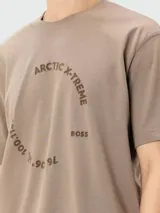 Camiseta de manga corta color beige con cuello redondo y un estampado gráfico en el pecho con texto que incluye "ARCTIC X-TREME" y coordenadas geográficas.