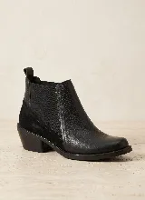 Bota tipo Chelsea de cuero negro con paneles laterales elásticos y taco bajo cuadrado. Presenta una combinación de texturas en el cuero y una presilla trasera para facilitar el calce.
