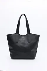 Cartera tipo tote de diseño amplio y textura símil cuero, con asas trenzadas y terminaciones artesanales.