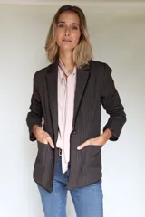 Blazer femenino forrado de corte tradicional, levemente entallado en la cintura, con mini hombreras, botón metálico con escudo y terminación desflecada.