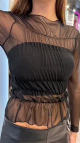 Top negro de manga larga confeccionado en tela de malla transparente, con diseño fruncido en el torso y detalles de volados.