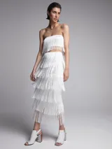 Conjunto de top bandeau y falda midi, ambos blancos con flecos.