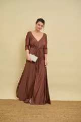 Vestido largo color marrón de silueta fluida, con escote en V pronunciado, mangas tres cuartos de tul con detalles sutiles, nudo drapeado en el centro del pecho y tajo delantero en la falda.