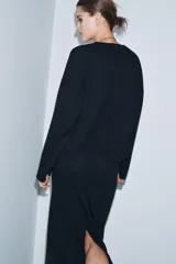 Falda midi de tiro medio confeccionada en tejido soft, con cintura elástica y abertura en la parte posterior.