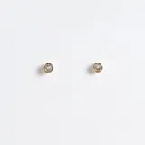 Par de aros dorados circulares con cristal claro en el centro, de acero con acabado en oro de 18k.