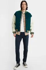 Jean de corte skinny y tiro medio, en color azul oscuro con acabado uniforme. Presenta costuras reforzadas y cierre frontal con botón y cremallera.