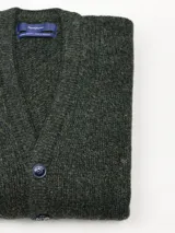 Cardigan de punto grueso con cuello en V y cierre frontal de botones. Presenta un diseño jaspeado en tonos grises y un pequeño bordado en el pecho.