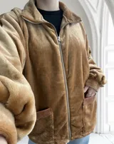 Campera de terciopelo color camel, con cierre frontal, cuello alto y bolsillos laterales con ribete de cuero sintético.