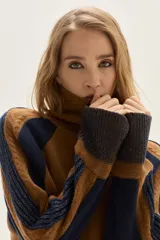 Polera de cuello alto confeccionada en lana lambswool, con diseño de bloques de color en tonos beige y marrón. Presenta mangas raglán con textura acanalada y detalles en hilo metalizado lurex.