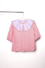 Camisa de lino texturado con diseño a rayas verticales rojas y blancas, cuello babero desmontable en color lila con volados y mangas cortas abullonadas.