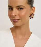 Caravana femenina de tamaño mediano, con forma de flor en color bordó y centro dorado.