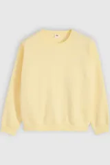 Buzo de cuello redondo color amarillo pastel, con mangas largas y puños y cintura elastizados de ajuste acanalado.