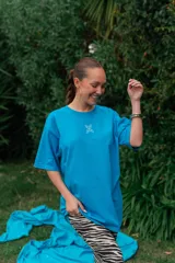 Remerón de algodón color celeste, de corte oversize, con mangas cortas amplias y pequeño estampado lineal en el centro del pecho.