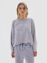 Buzo de felpa con efecto lavado acid wash, de corte oversized y manga larga. Presenta estampa frontal con texto y estrellas.