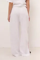 Pantalon de lino color marrón con costuras blancas decorativas a lo largo de las piernas y corte amplio.