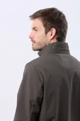 Campera repelente al agua y cortaviento de color negro, con capucha desmontable, cierre frontal y parche circular en el pecho.