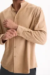 Camisa de manga larga color beige con cuello mao y cierre frontal con botones.